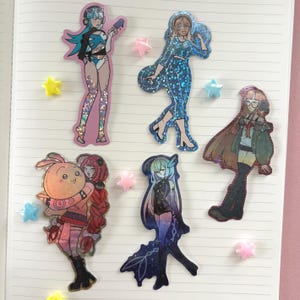 Puede incluir: Una colección de pegatinas holográficas con personajes de estilo anime en varios atuendos. Las pegatinas están sobre un fondo de papel de cuaderno rayado, con adornos en forma de estrella. Los personajes son en tonos de azul, rosa y negro.