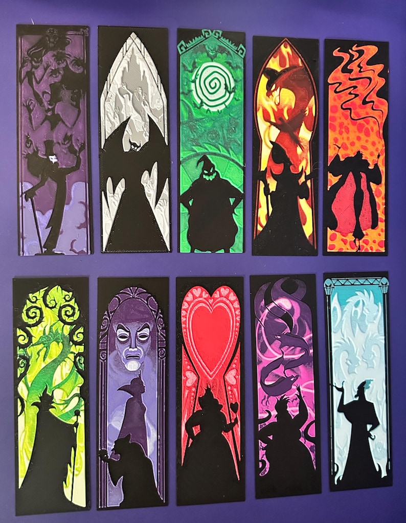 Puede incluir: Una colecci&oacute;n de diez marcap&aacute;ginas rectangulares con ilustraciones coloridas de personajes al estilo vidriera. Cada marcap&aacute;ginas tiene un borde negro y un dise&ntilde;o &uacute;nico, incluyendo siluetas y fondos detallados en tonos de morado, verde, rojo y azul.