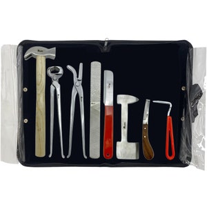 May include: A set of farrier tools, including a hammer, nippers, rasp, and hoof knife, arranged on a black background within a zippered case. The tools have wooden or metal handles and are designed for equine hoof care.