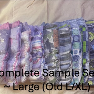 Puede incluir: Un conjunto de ocho pañales de tela reutilizables en varios colores y patrones, incluyendo estrellas, rayas y diseños geométricos. Los pañales están etiquetados como "Complete Sample Sets ~ Large (Old L/XL)".