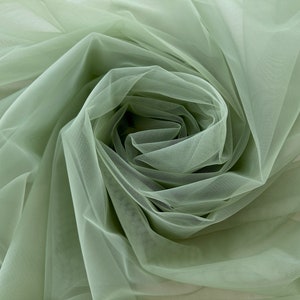 May include: A close-up of a sage green tulle fabric, showing the soft, delicate texture and the way it drapes.