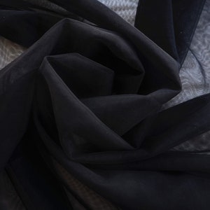 May include: Black sheer fabric with a soft, delicate texture. The fabric is draped and folded, creating a flowing and elegant look.