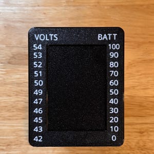 May include: A black rectangular gauge with rounded corners, displaying "VOLTS" and "BATT" at the top. Numerical values from 42 to 54 are listed on the left, and 0 to 100 on the right. The center is a black rectangle.