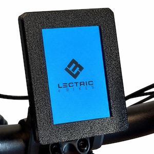 May include: Black rectangular display screen with the text "LECTRIC e BIKES" on a blue background. The screen is mounted on a black handlebar, with a black textured frame. The display shows a logo.