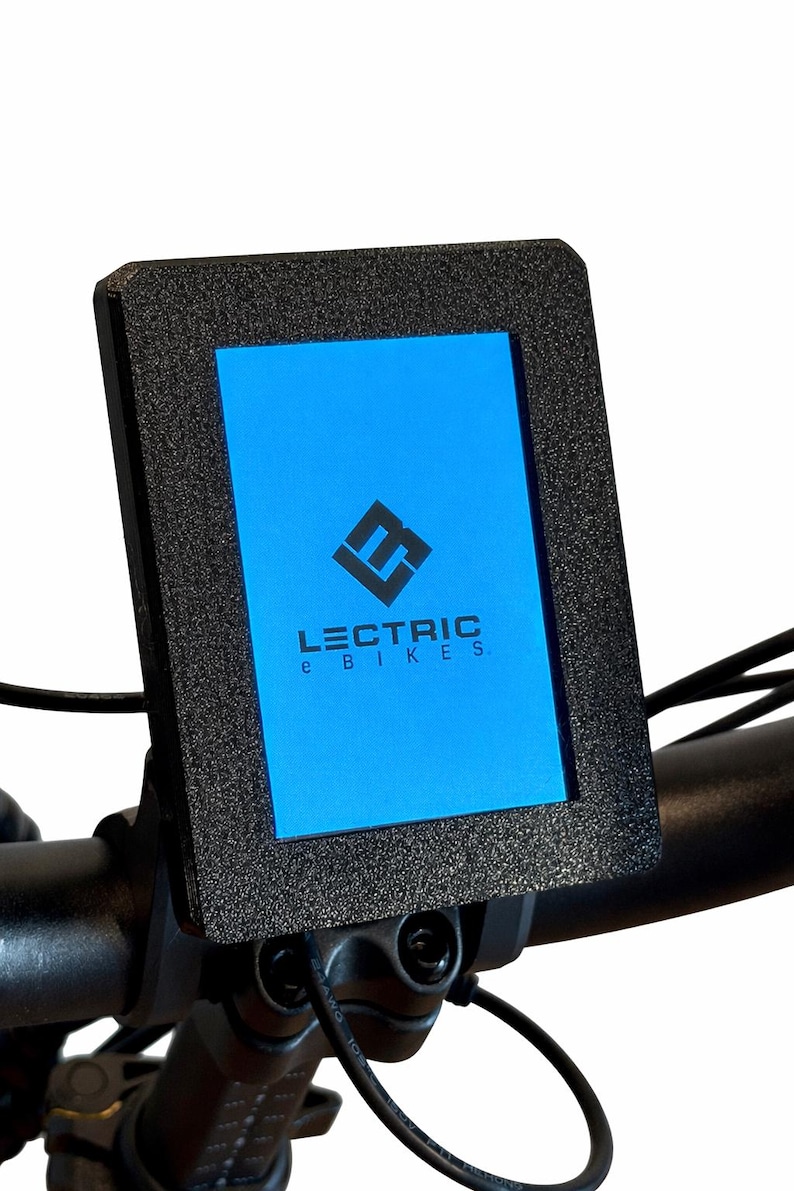 May include: Black rectangular display screen with the text "LECTRIC e BIKES" on a blue background. The screen is mounted on a black handlebar, with a black textured frame. The display shows a logo.