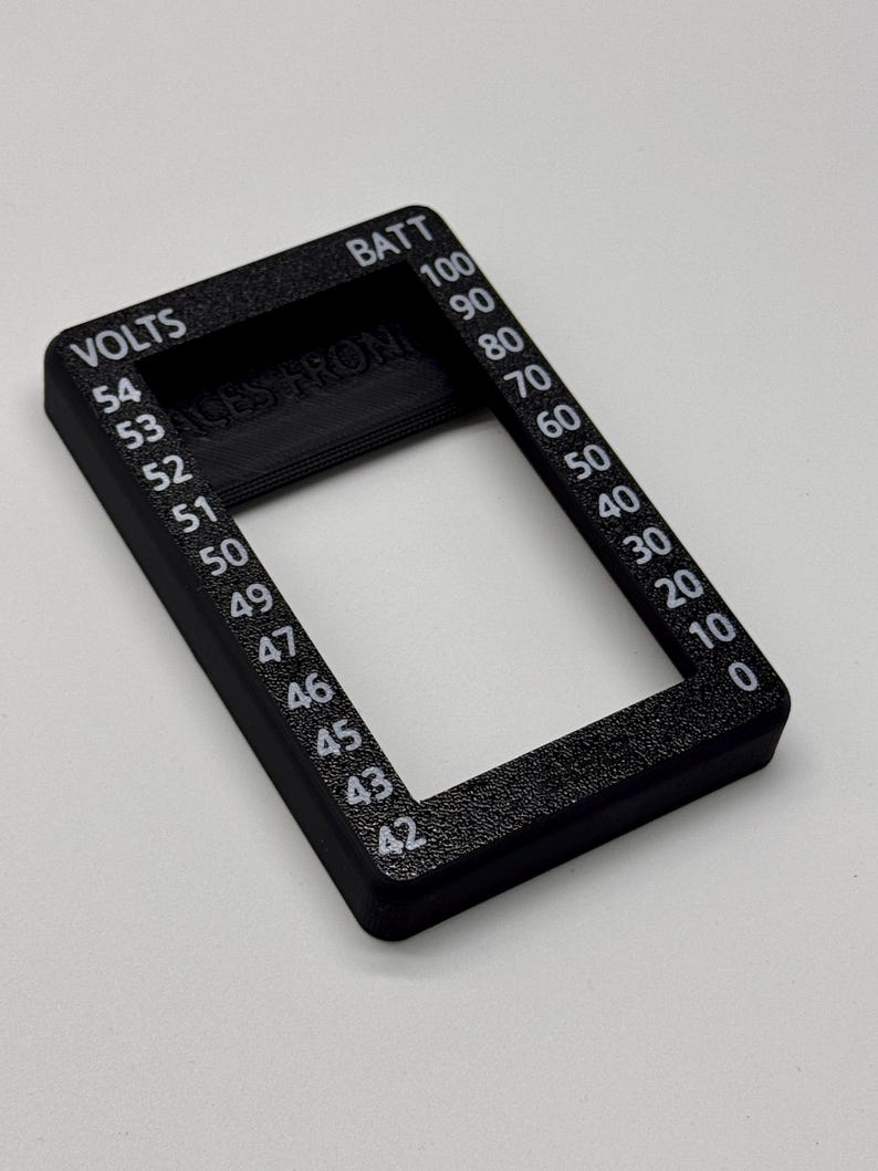 May include: A black rectangular gauge with white text indicating voltage and battery levels. The gauge reads "VOLTS" and "BATT" with numerical values from 0 to 100. The text "ALES FROM" is also visible.