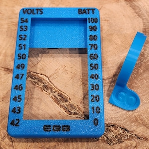 May include: A blue plastic gauge with a rectangular window and a scale marked "VOLTS" and "BATT". The gauge has a black label that reads "EGG".
