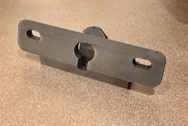 May include: A black metal bracket with a keyhole and two oval-shaped holes. The bracket is designed to be mounted to a wall or surface.