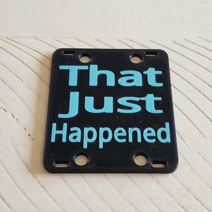 May include: Black plastic sign with the text "That Just Happened" in light blue lettering.