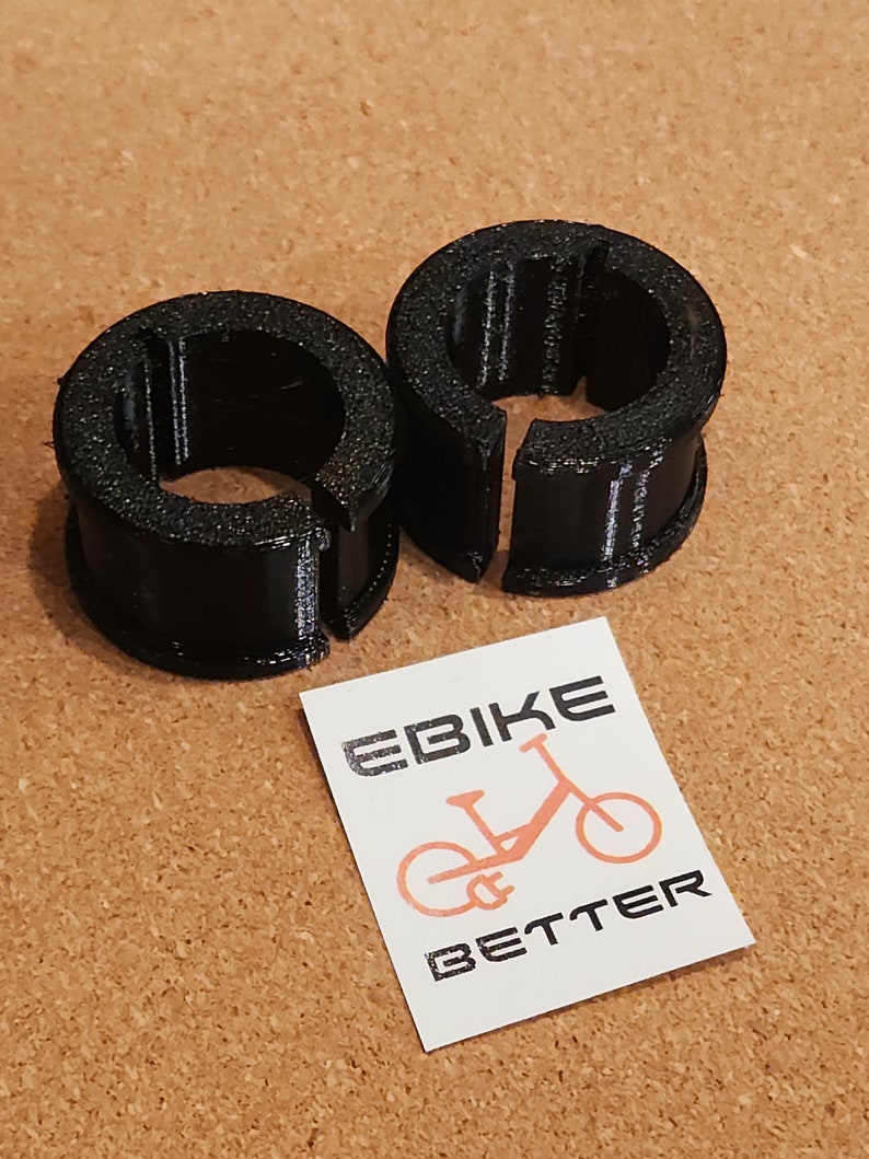 Op de afbeelding: Twee zwarte plastic ringen met een split aan &eacute;&eacute;n kant. De ringen zijn ontworpen om te worden gebruikt als kabelbinders of om items te beveiligen.