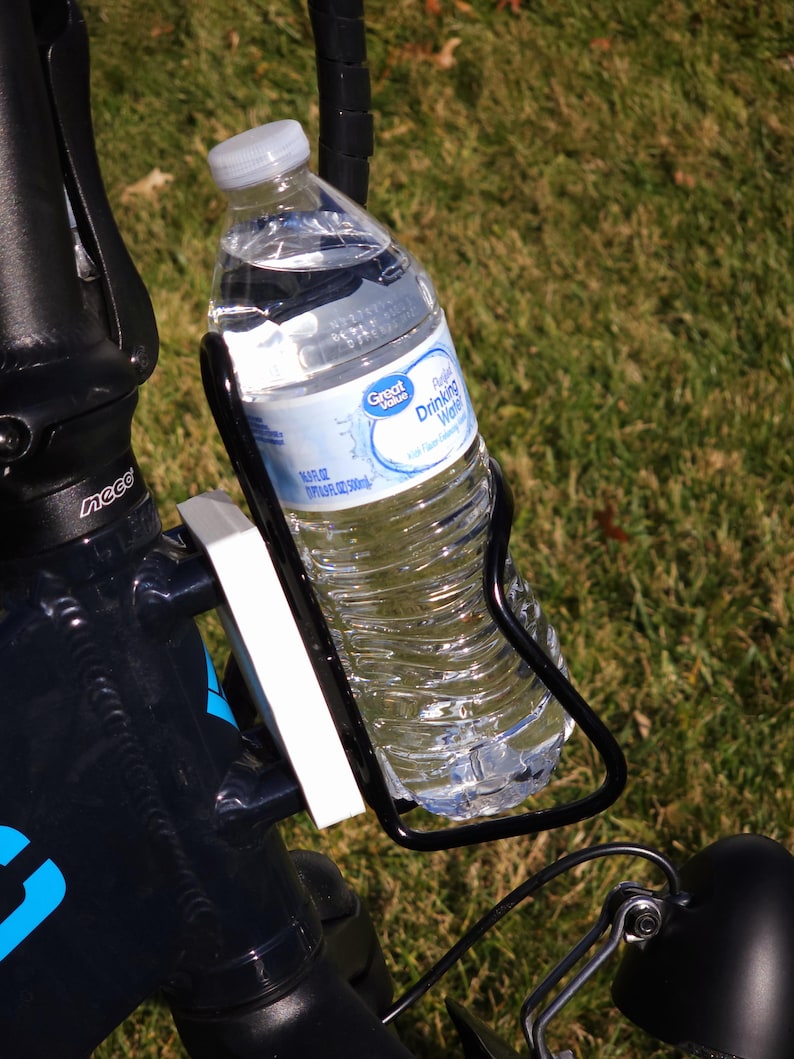 May include: A black bicycle water bottle holder with a clear plastic water bottle inside. The bottle is labeled "Great Value Purified Drinking Water".