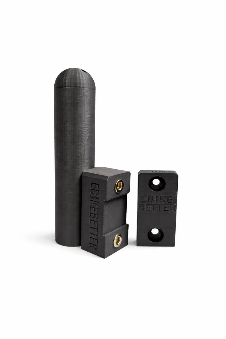 May include: Three black e-bike accessories are displayed against a white background. The items include a tall, cylindrical piece and two rectangular pieces with the text "EBIKE BETTER". The rectangular pieces have holes.