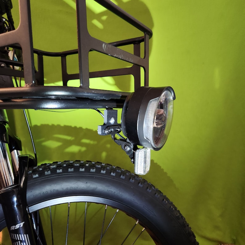 May include: A black bicycle with a front basket and a headlight. The bicycle has a black tire with white lettering.