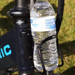 May include: A black bicycle frame with a black water bottle holder and a clear plastic water bottle with a blue and white label that says "Pure Drinking Water".