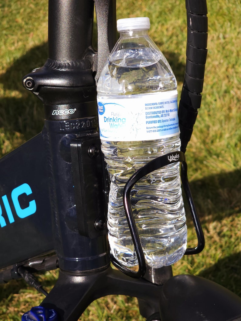 May include: A black bicycle frame with a black water bottle holder and a clear plastic water bottle with a blue and white label that says "Pure Drinking Water".