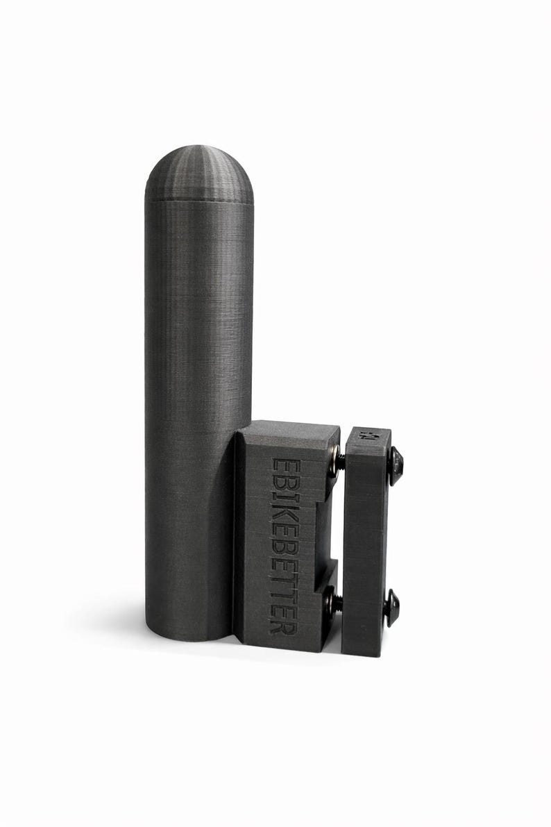 May include: A dark gray, cylindrical object with a rounded top, connected to a rectangular block with the text "EBIKEBETTER". The object appears to be made of a textured material, possibly plastic or metal. The design suggests a mechanical or industrial component.