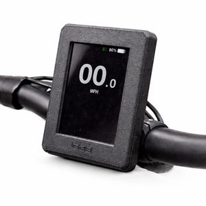 May include: A black digital display showing "00.0 MPH" with a battery indicator at 90%. The display is mounted on a black handlebar. The screen is in a black rectangular frame.