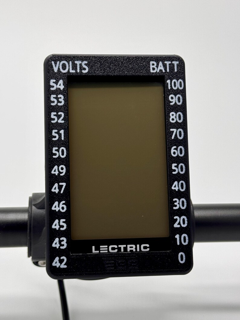 May include: A black digital display with white text indicating voltage and battery levels. The display reads "VOLTS" and "BATT" with corresponding numerical values. The brand name "LECTRIC" is visible on the display.