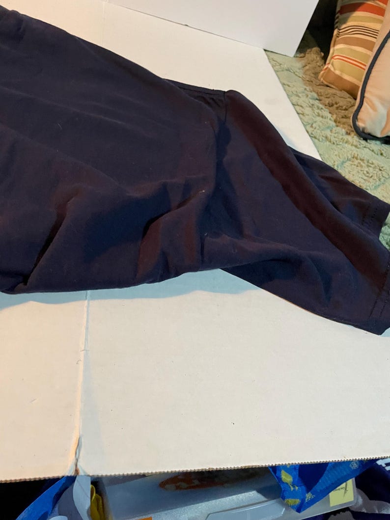 K&ouml;nnte beinhalten: Ein dunkelblaues T-Shirt mit kurzen &Auml;rmeln und Rundhalsausschnitt. Der Stoff ist glatt und blickdicht und weist nat&uuml;rliche Falten auf der Oberfl&auml;che auf. Das Kleidungsst&uuml;ck liegt flach und zeigt die Schulternaht sowie die &Auml;rmelkonstruktion.