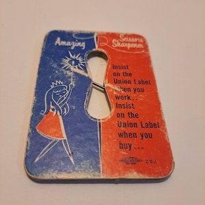 May include: A vintage red and blue cardboard scissor sharpener with a cartoon illustration of a girl holding a sparkler. The text on the card reads "Amazing" and "Scissors Sharpener". The text also says "Insist on the Union Label when you work... Insist on the Union Label when you buy... 252".