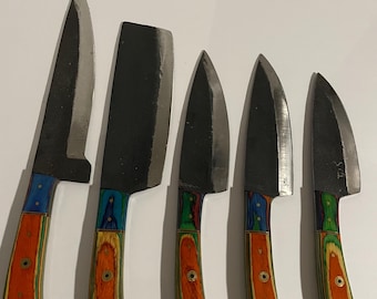 May include: A set of five kitchen knives with dark blades and colorful, layered wooden handles. The handles feature a mix of red, orange, green, and blue hues. The blades vary in shape and size, suitable for various culinary tasks.