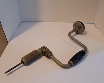 May include: A vintage hand drill with a black wooden handle and a silver metal body. The drill bit is extended and ready to use.
