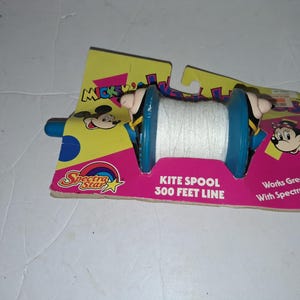 May include: A vintage Mickey Mouse kite spool with 300 feet of line. The spool is blue with white string, and the packaging is yellow and pink with Mickey Mouse graphics. The packaging also says "Works Great With Spectra Kites."