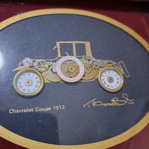 May include: A framed artwork depicting a vintage Chevrolet Coupe from 1912, constructed from intricate clockwork gears and mechanisms. The artwork is signed "T. Ronchetti" and includes the text "Chevrolet Coupe 1912".