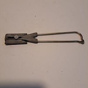 May include: A silver metal wire connector with a gray plastic housing. The connector has a loop on one end and a flat, rectangular shape on the other end.