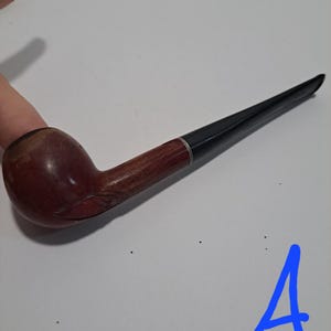 Op de afbeelding: Een bruine houten pijp met een zwarte steel. De pijp heeft een gesneden ontwerp op de kom.