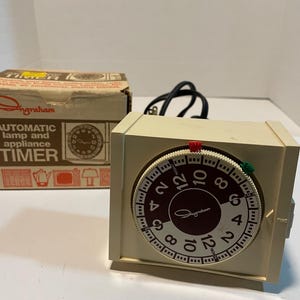 May include: A white Ingraham automatic lamp and appliance timer with a round dial and a black cord. The dial has numbers 1 through 12 and the words "ON" and "OFF".
