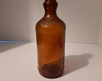 May include: A brown glass bottle with a red and white cap. The bottle has the word "JIF" embossed on the front.