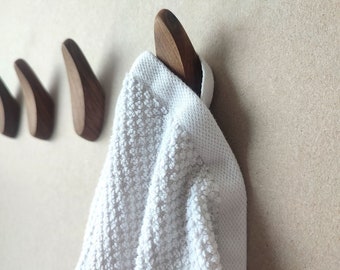 May include: Three wooden wall hooks in different sizes, with a white towel hanging on the largest hook.