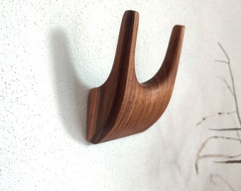 May include: A wooden wall hook with a unique curved design. The hook is made of dark brown wood and has a smooth finish.