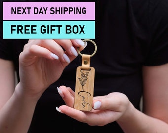 May include: A wooden keychain with a leather strap and a metal ring. The keychain is engraved with the name "Carla" and a floral design.