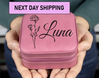 May include: A pink, square-shaped jewelry box with a zipper closure. The box is personalized with the name "Luna" and a floral design.
