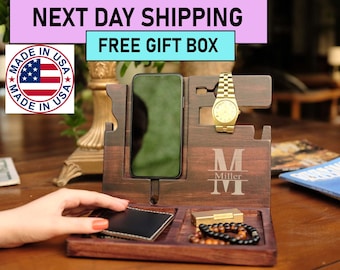 May include: A wooden phone stand with a watch holder, a small tray for a lighter or other small items, and a larger tray for a wallet or keys. The stand is personalized with the letter "M" and the name "Miller".