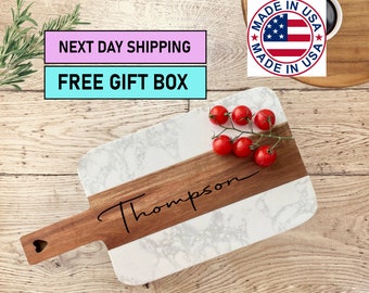 May include: White marble serving board with a wooden handle and a brown wood inlay. The board is personalized with the name "Thompson".
