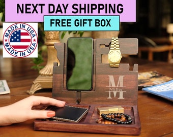 May include: A wooden phone stand with a watch holder, a small tray for a lighter or other small items, and a larger tray for a wallet or keys. The stand is personalized with the letter "M" and the name "Miller".