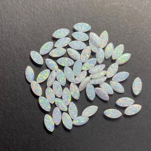 May include: A collection of white oval-shaped opal gemstones with iridescent rainbow colors.