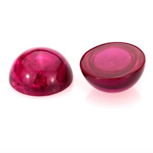 May include: Two round, pink cabochon gemstones. One is shown from the top and the other from the side.