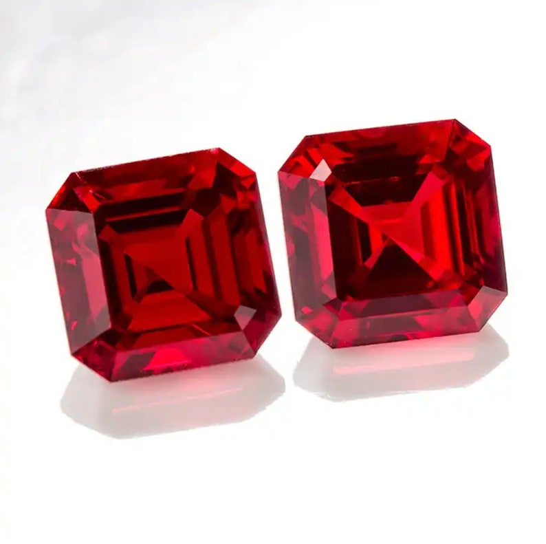 May include: Two vibrant red square-shaped gemstones with a faceted cut.