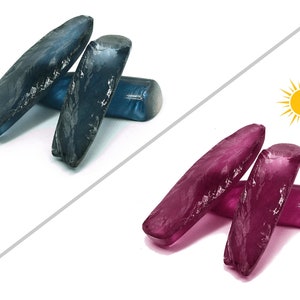 May include: Two rough cut blue sapphires and two rough cut pink sapphires. The sapphires are arranged in two stacks, one on top of the other. The sapphires are on a white background.