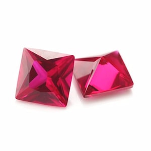Könnte beinhalten: Zwei leuchtend rosa quadratische Edelsteine mit Facettenschliff.