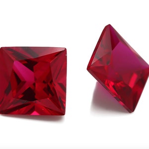 May include: Two red square-shaped gemstones with a faceted cut.