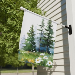 May include: A white outdoor flag with a watercolour painting of a forest scene. The artwork shows tall green pine trees, a field of daisies, and a misty background. The flag is mounted on a white pole with a black bracket.