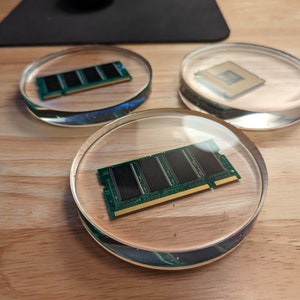 May include: Three clear glass coasters with a green circuit board inside each. The circuit boards are different sizes and shapes.