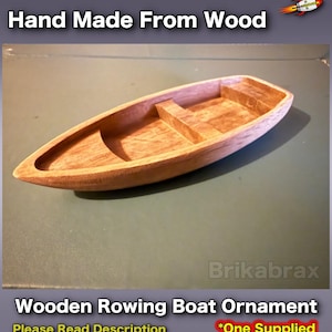 May include: A wooden rowing boat ornament, handcrafted from light brown wood. The boat has a detailed design. The text "Hand Made From Wood" is at the top. The text "Wooden Rowing Boat Ornament" is at the bottom.