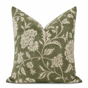 Può includere: Un cuscino quadrato con una base in tessuto verde oliva scuro e un motivo floreale a contrasto color crema. Il design presenta grandi e complessi motivi botanici, inclusi fiori stilizzati e tralci di foglie su tutta la superficie del cuscino.