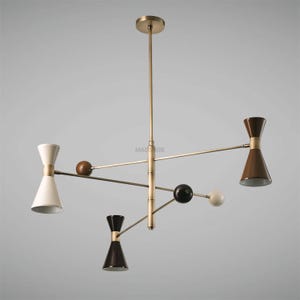 May include: A modern, gold-toned chandelier with five lights. The lights are arranged in a geometric pattern and feature a combination of white, black, and brown shades. The chandelier has a long, slender stem and a circular canopy.